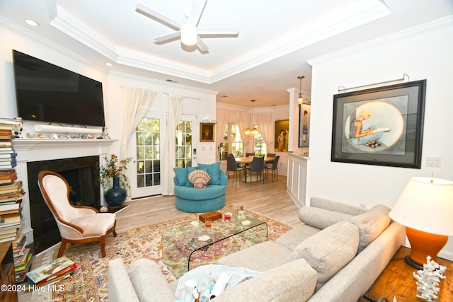 living room featuring ceiling fan, a raised ceiling, and light wood-type flooring