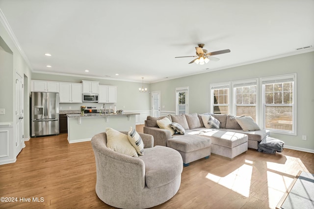 living room featuring ceiling fan with notable chandelier, ornamental molding, and light hardwood / wood-style flooring