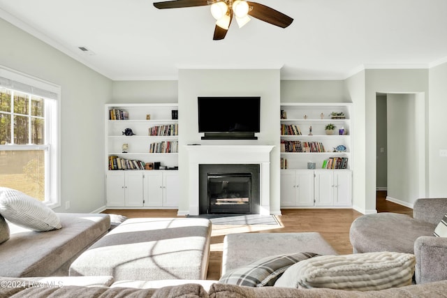 living room featuring light hardwood / wood-style floors, ceiling fan, and crown molding