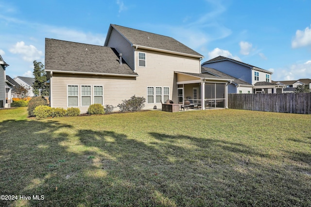 back of house featuring a lawn and a sunroom