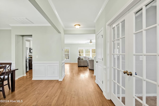 hall featuring french doors, light wood-type flooring, and ornamental molding