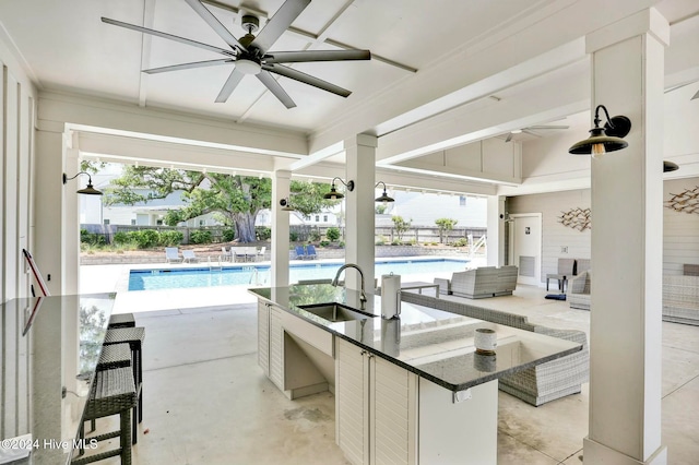 view of patio / terrace featuring ceiling fan, a community pool, and an outdoor wet bar