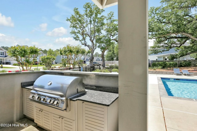 view of patio with an outdoor kitchen, a fenced in pool, and a grill