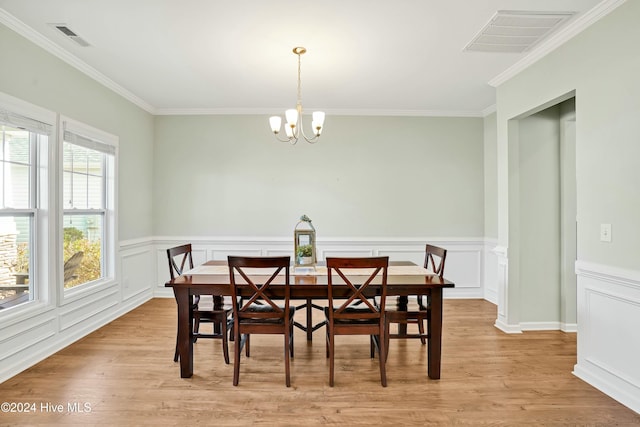 dining area with crown molding, light hardwood / wood-style floors, and an inviting chandelier