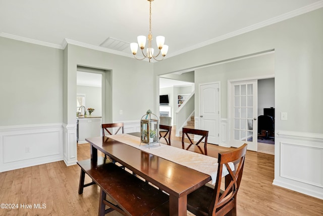 dining area featuring light wood-type flooring, an inviting chandelier, and crown molding