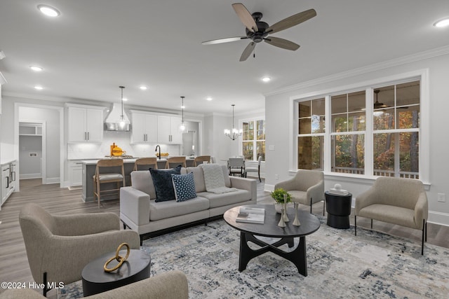 living room featuring sink, ceiling fan with notable chandelier, light hardwood / wood-style flooring, and ornamental molding