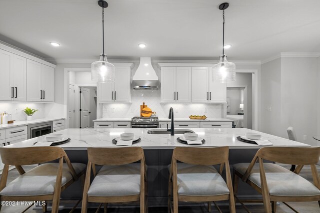 kitchen featuring pendant lighting, a center island with sink, white cabinetry, and sink