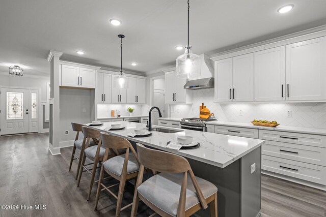 kitchen with white cabinets, wall chimney range hood, sink, and appliances with stainless steel finishes