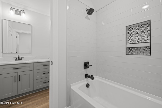 bathroom featuring vanity, wood-type flooring, and tiled shower / bath