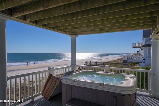 wooden terrace with a beach view, a water view, and a hot tub