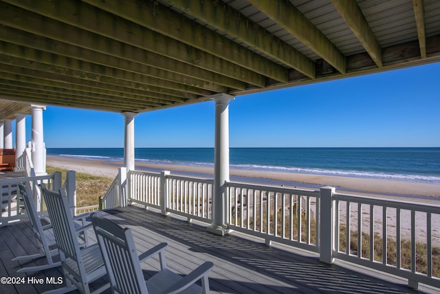 wooden terrace featuring a beach view and a water view