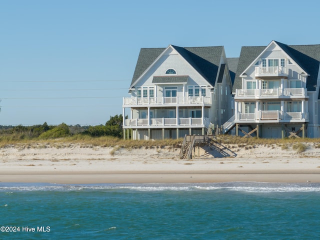 rear view of house featuring a water view and a beach view