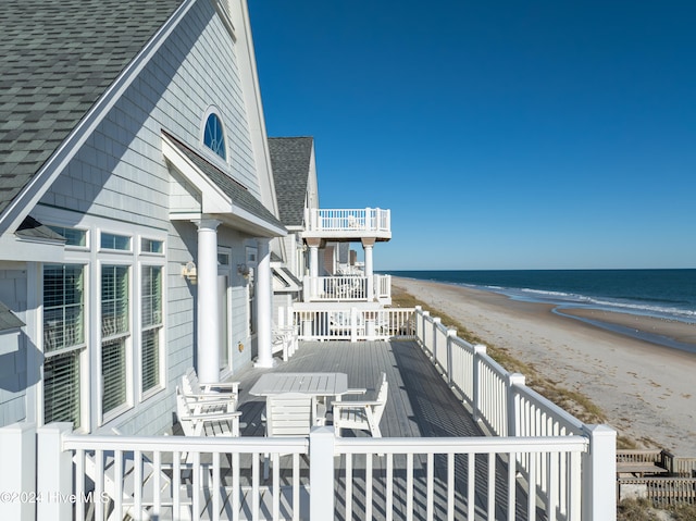 wooden deck with a water view and a beach view