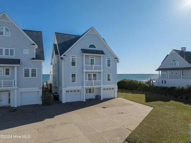 view of front of property featuring a front yard, a water view, and a balcony