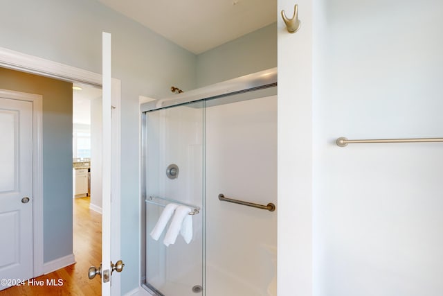 bathroom with hardwood / wood-style floors and a shower with door