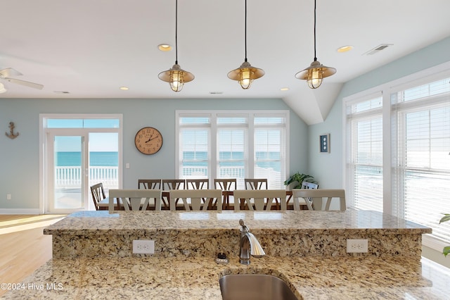 kitchen featuring pendant lighting, plenty of natural light, a water view, and light hardwood / wood-style floors