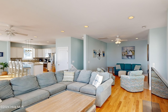 living room with ceiling fan, sink, and light hardwood / wood-style flooring