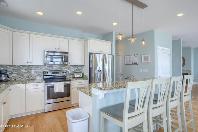 4316 Island Dr, North Topsail Beach, NC 28460 - kitchen with appliances with stainless steel finishes, decorative backsplash, light wood-style floors, white cabinets, and recessed lighting