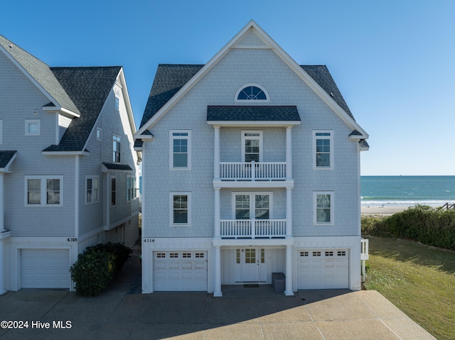 view of front of property featuring a balcony, a water view, a view of the beach, and a garage