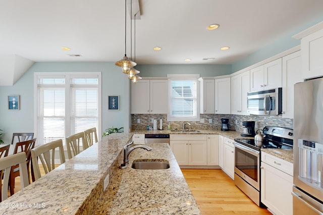 kitchen featuring stainless steel appliances, sink, pendant lighting, white cabinets, and plenty of natural light