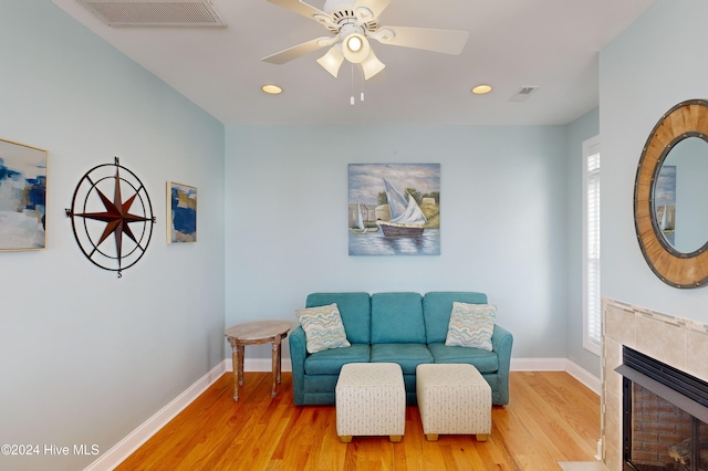 living room with a healthy amount of sunlight, a fireplace, ceiling fan, and light hardwood / wood-style floors