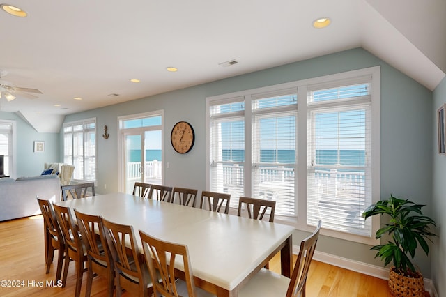 dining area featuring ceiling fan, a water view, light hardwood / wood-style floors, and lofted ceiling