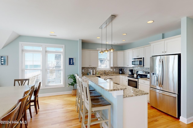 4316 Island Dr, North Topsail Beach, NC 28460 - kitchen with stainless steel appliances, light wood-type flooring, backsplash, pendant lighting, and light stone countertops
