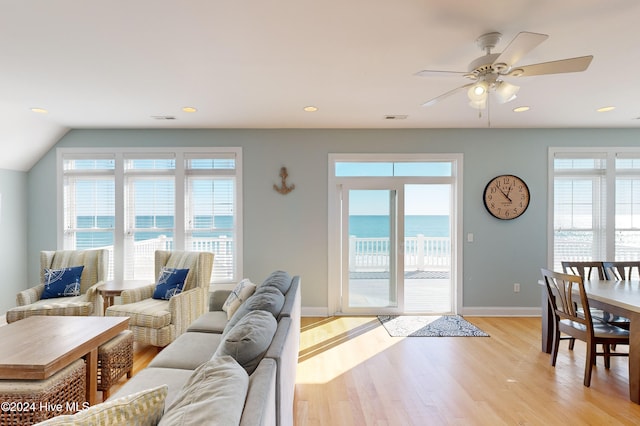 living room featuring vaulted ceiling, ceiling fan, a view of the beach, a water view, and light hardwood / wood-style flooring