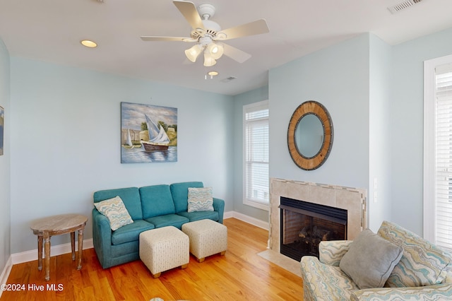 living room with a tiled fireplace, ceiling fan, and hardwood / wood-style flooring