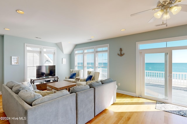 living room featuring a view of the beach, a water view, light hardwood / wood-style flooring, and ceiling fan