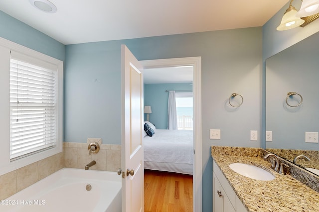 bathroom featuring hardwood / wood-style flooring, vanity, a tub, and a wealth of natural light