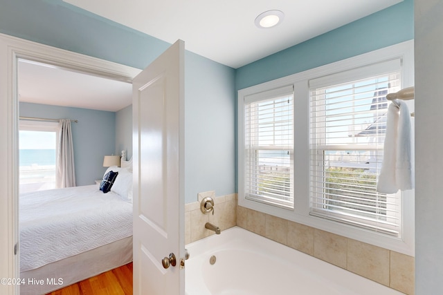 bathroom with wood-type flooring, a bathtub, and plenty of natural light