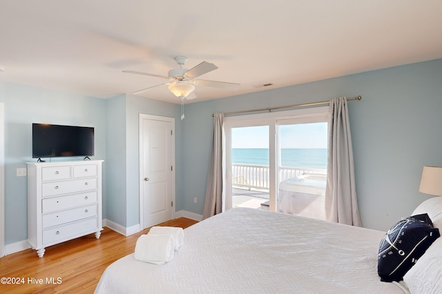 bedroom featuring access to outside, light wood-type flooring, a water view, and ceiling fan