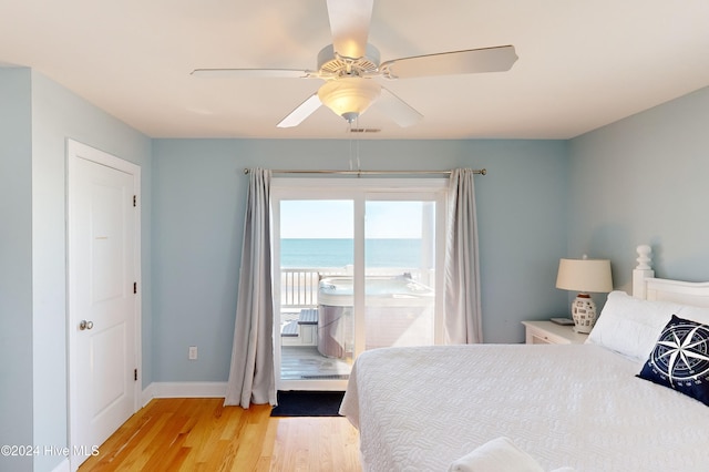 bedroom featuring access to exterior, ceiling fan, a water view, and light hardwood / wood-style flooring