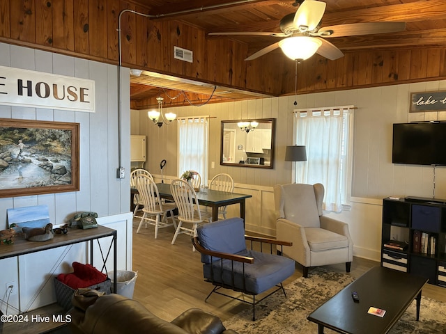 living room featuring beam ceiling, ceiling fan with notable chandelier, light hardwood / wood-style flooring, and wooden ceiling