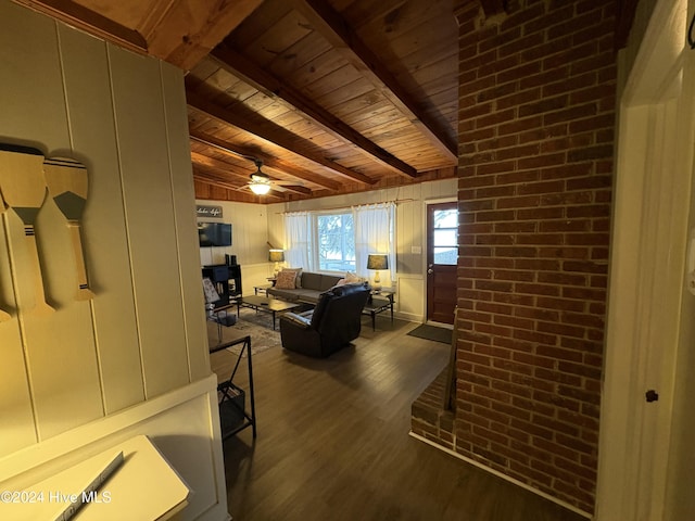 living room with ceiling fan, dark hardwood / wood-style flooring, beamed ceiling, brick wall, and wood ceiling