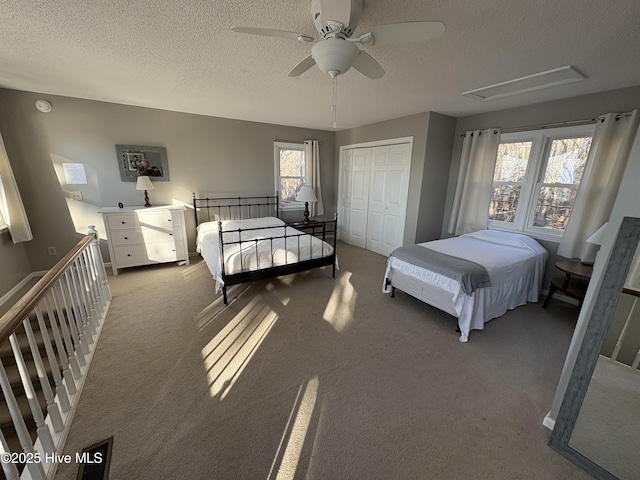 carpeted bedroom with a textured ceiling, a closet, and ceiling fan