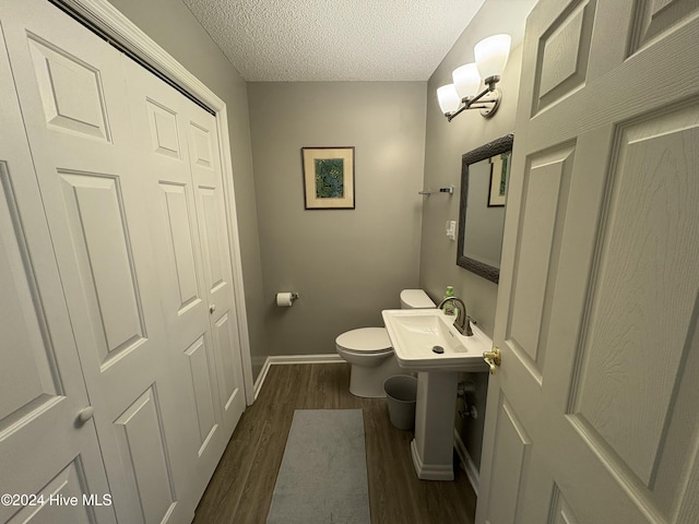 bathroom with toilet, a textured ceiling, and hardwood / wood-style flooring