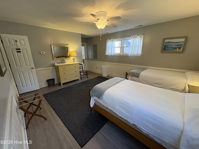 bedroom with a textured ceiling, electric panel, ceiling fan, and dark hardwood / wood-style floors