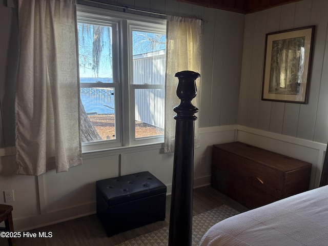 bedroom with hardwood / wood-style floors and a water view