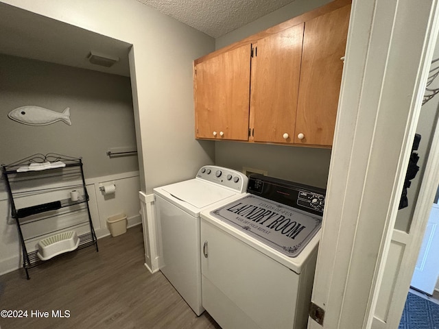 washroom featuring washer and dryer, dark hardwood / wood-style floors, cabinets, and a textured ceiling