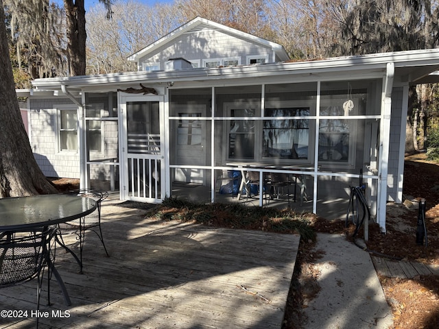 rear view of house featuring a wooden deck and a sunroom