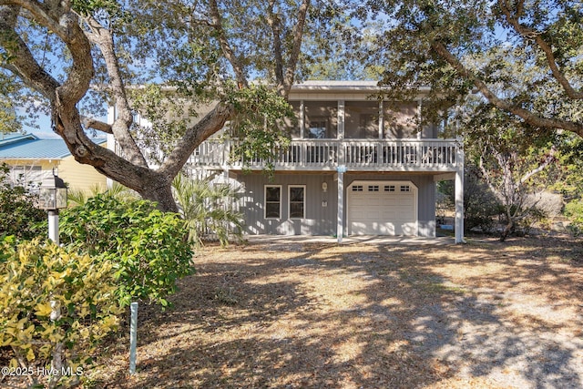 back of property featuring a sunroom, an attached garage, and driveway