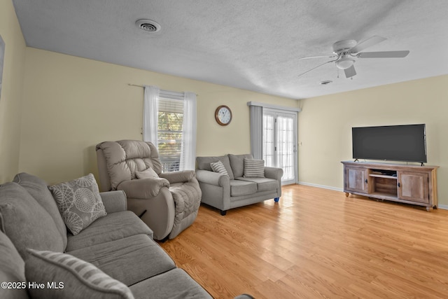 living area featuring light wood-type flooring, a healthy amount of sunlight, visible vents, and a textured ceiling