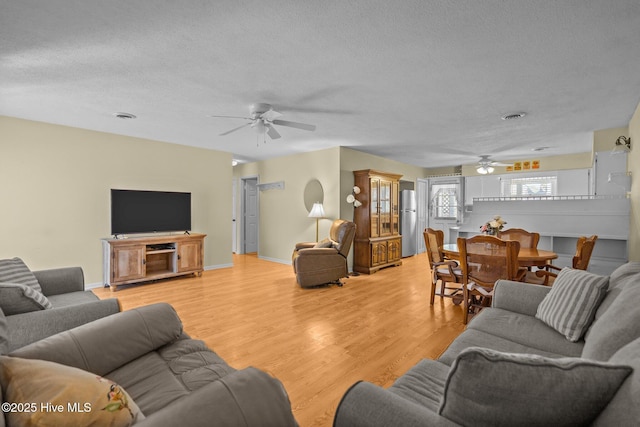 living room with a textured ceiling, visible vents, and light wood-style floors