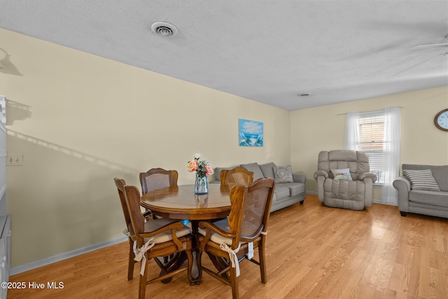 dining area featuring visible vents, a textured ceiling, light wood-style flooring, and baseboards