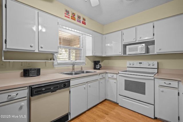 kitchen with light countertops, white appliances, a sink, and white cabinets