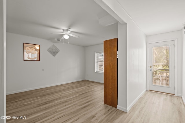 unfurnished room with a ceiling fan, light wood-type flooring, and baseboards