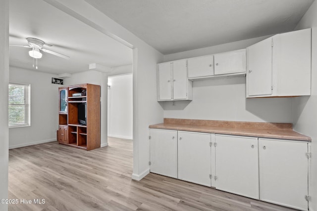 kitchen featuring light wood finished floors, baseboards, white cabinetry, and light countertops