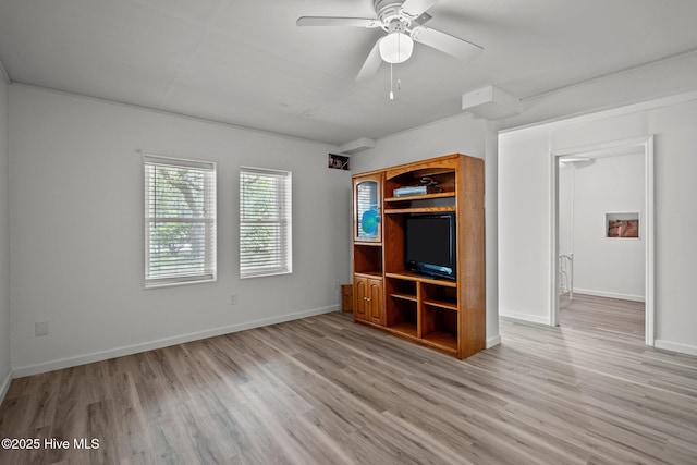 interior space with a ceiling fan, light wood-style flooring, and baseboards